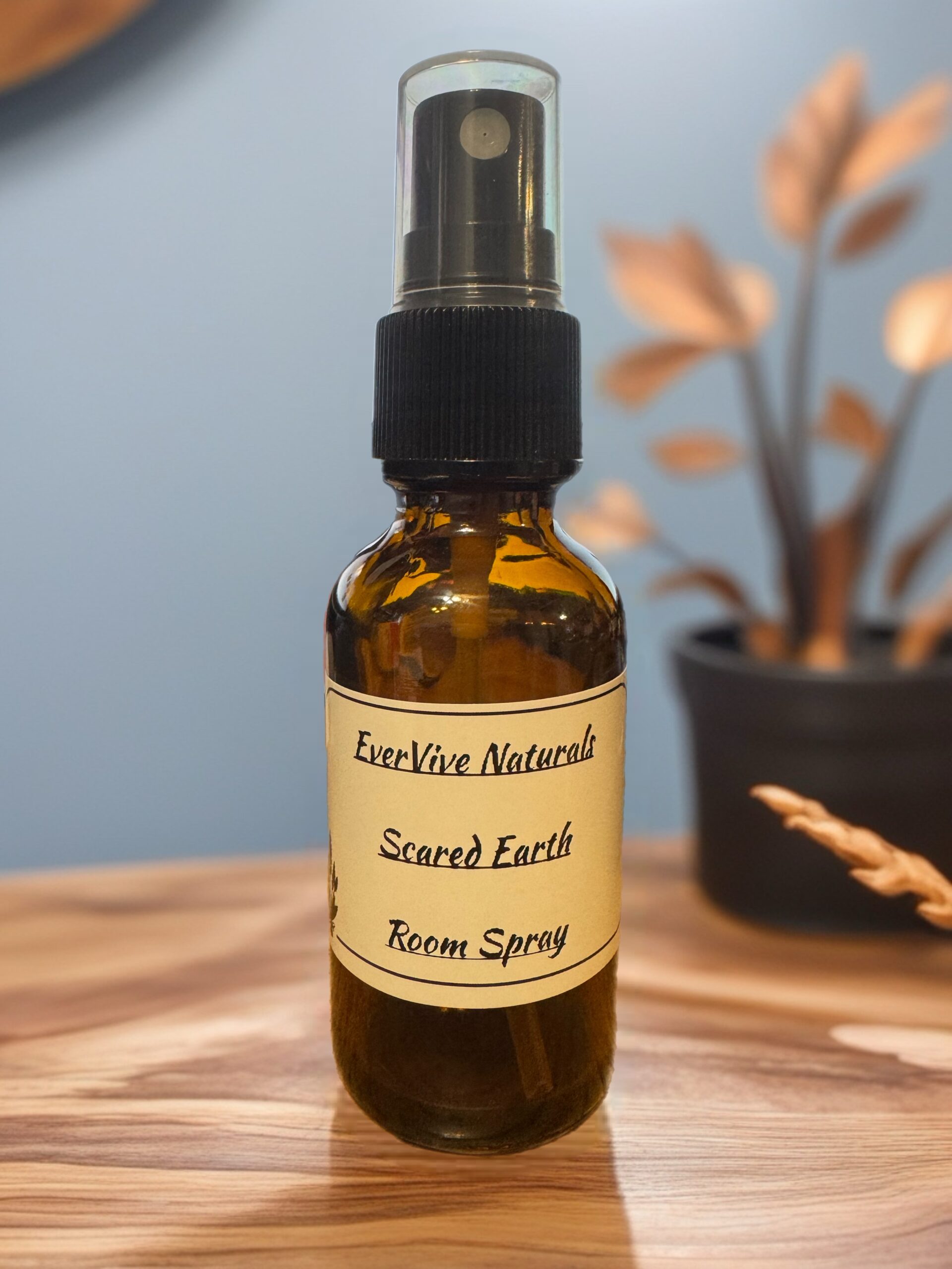 Sacred Earth Room Spray โ grounding essential oil mist with frankincense, patchouli, and basil on wood altar with crystals and greenery